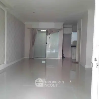 Spacious empty living room with tiled flooring and sliding glass doors leading to a balcony.