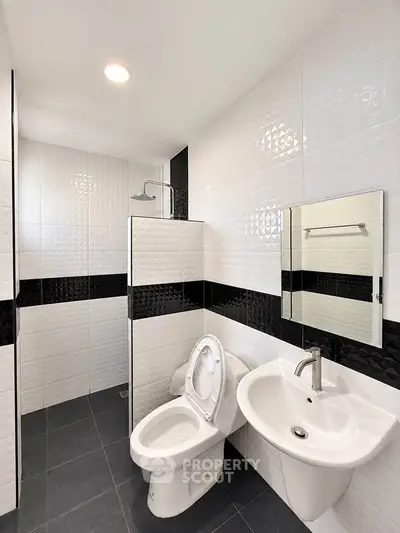Modern bathroom with sleek black and white tiles and contemporary fixtures.
