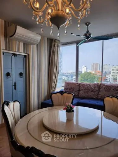 Luxurious corner unit with panoramic city views, featuring an elegant chandelier, large windows, and plush seating area.
