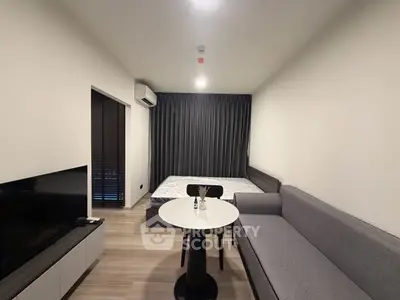 Modern studio apartment with cozy living area and bed, featuring sleek furniture and neutral tones.
