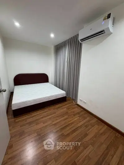 Spacious bedroom with wooden flooring and modern air conditioning unit.