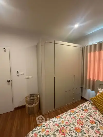 Cozy bedroom with modern wardrobe and floral bedding in a well-lit space.