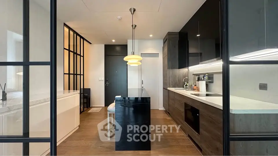 Modern kitchen with sleek design, featuring black cabinetry, island, and pendant lighting.