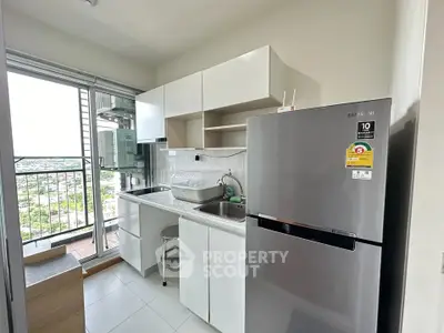 Modern kitchen with balcony view, featuring sleek cabinets and stainless steel fridge.