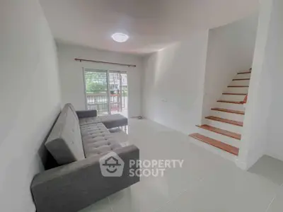 Modern living room with sleek staircase and comfortable sofa in bright space