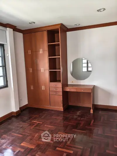Spacious bedroom with elegant wooden flooring and built-in wardrobe