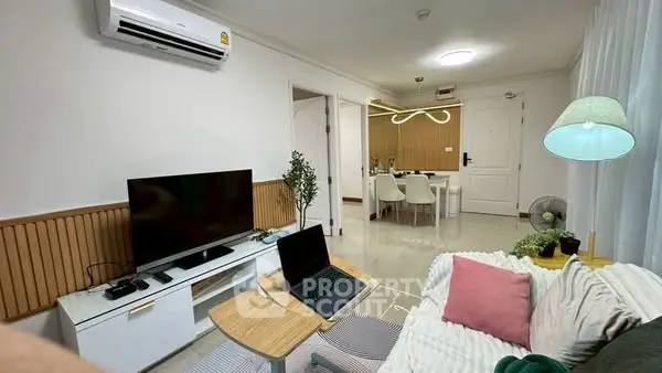 Modern living room with stylish decor and open dining area, featuring a sleek TV setup and cozy seating.