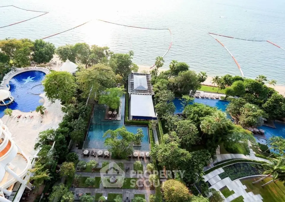 Stunning aerial view of luxury beachfront property with pools and lush gardens.