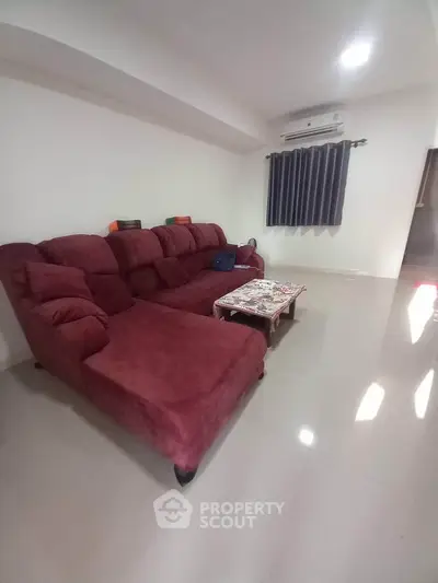 Spacious living room with plush red sofa and modern decor, perfect for relaxation and entertainment.