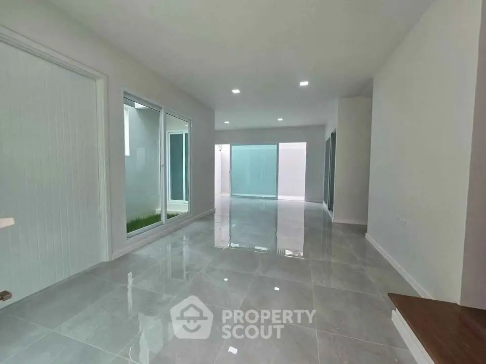 Spacious modern living room with glossy tiled floors and large windows for natural light.