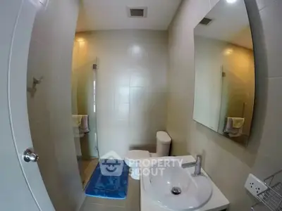 Modern bathroom with sleek fixtures and neutral tiles, featuring a glass shower enclosure.