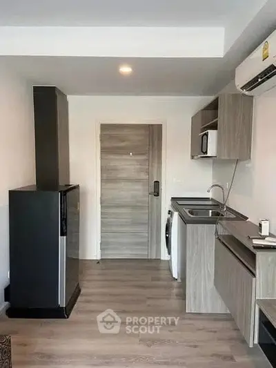 Modern compact kitchen with sleek cabinetry and integrated appliances in a stylish apartment.
