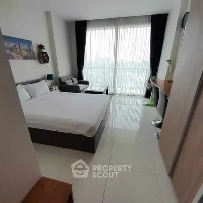 Modern bedroom with large windows and sleek furnishings in a bright apartment.