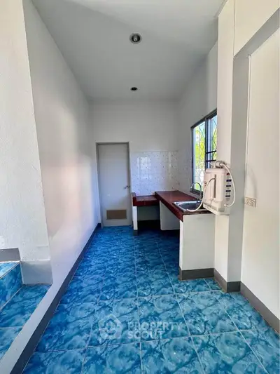 Bright kitchen with blue tiled floor and modern sink, featuring a compact layout and natural light.