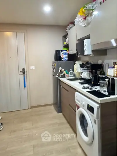 Modern kitchen with washing machine and sleek cabinetry in cozy apartment.