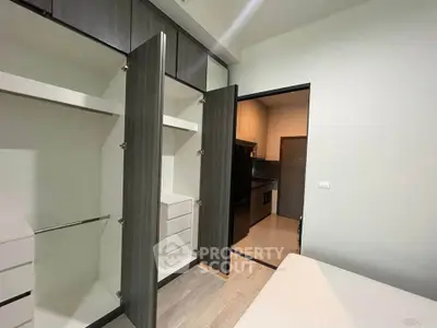 Modern bedroom with open closet and view into sleek kitchen