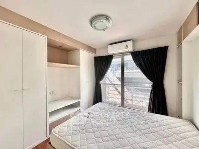 Bright bedroom with large window, built-in wardrobe, and air conditioning in modern apartment.