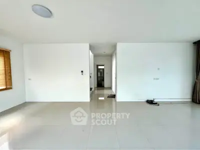 Spacious empty room with glossy tiled floor and large window, perfect for customization.