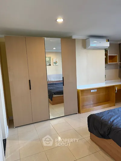 Modern bedroom with mirrored wardrobe and air conditioning unit