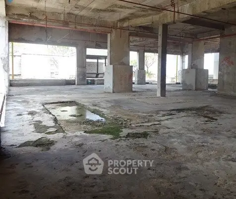Spacious unfinished industrial space with concrete floors and large windows.