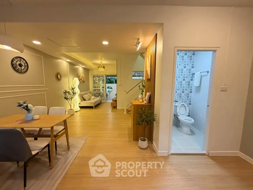 Spacious open-plan living and dining area with modern decor and adjacent bathroom.