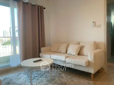 Cozy living room with beige sofa, round coffee table, and balcony view in modern apartment.