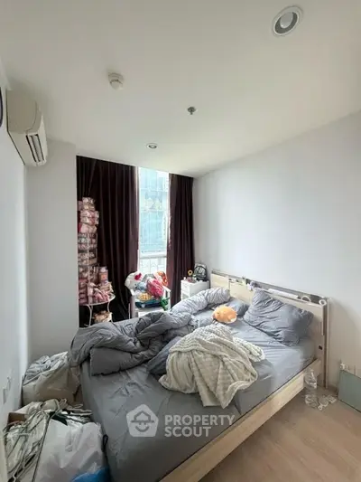 Cozy bedroom with large window and modern air conditioning unit, perfect for urban living.