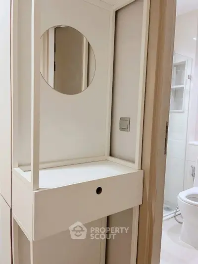 Modern bathroom with sleek vanity and round mirror, featuring a minimalist design and neutral tones.