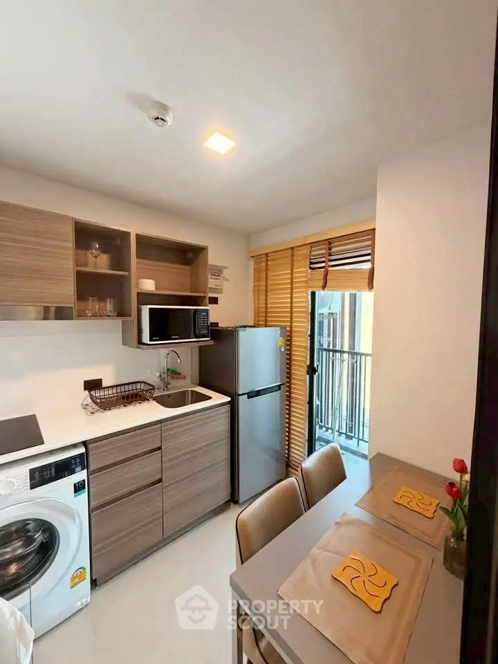 Modern kitchen with washing machine and balcony access in stylish apartment.