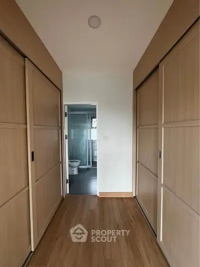 Spacious hallway with wooden sliding doors leading to a modern bathroom