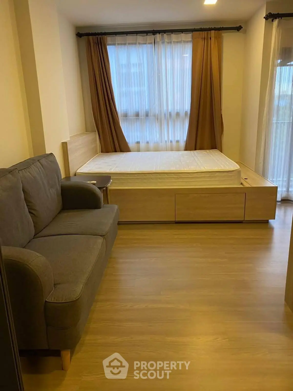 Cozy bedroom with wooden flooring and large windows for natural light