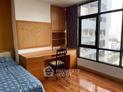 Spacious bedroom with large window and wooden flooring in modern apartment