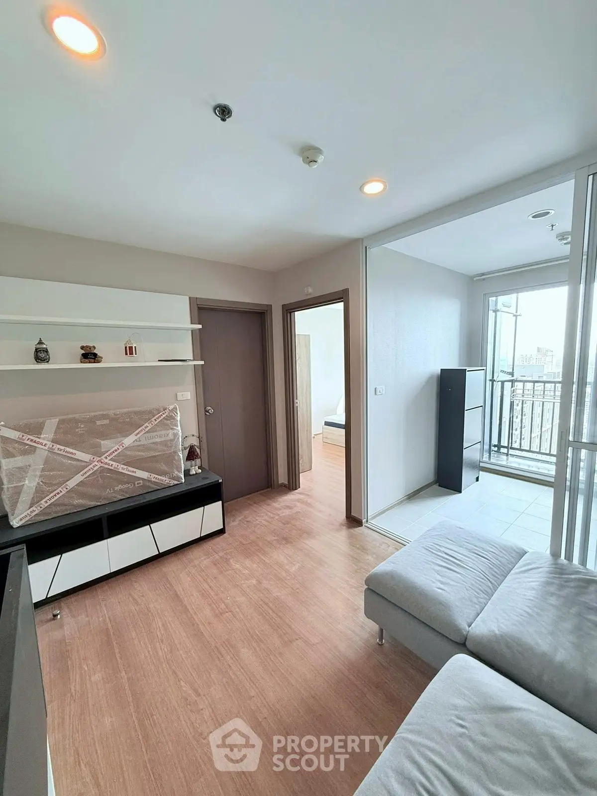 Modern living room with wooden flooring and balcony view in a stylish apartment.