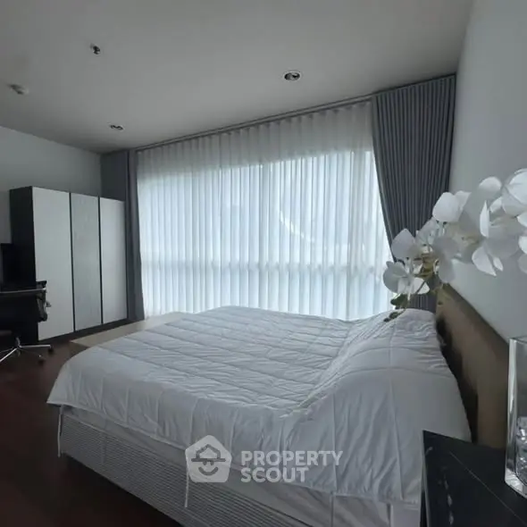 Spacious bedroom with modern decor and large window for natural light.
