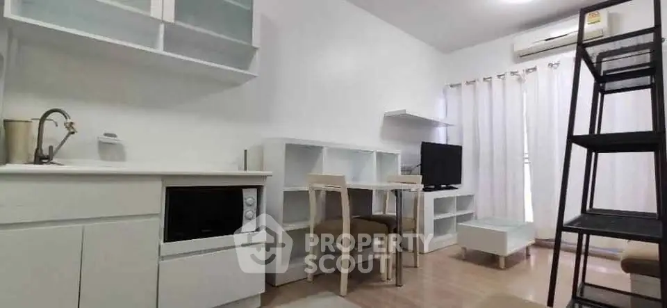 Modern living room with minimalist design, featuring a compact kitchen and stylish furniture.