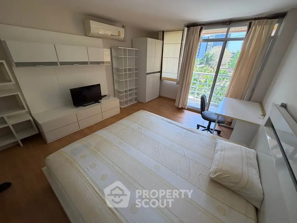 Spacious bedroom with modern furnishings and large window offering natural light and garden view.