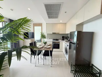 Modern open-layout kitchen with dining area, featuring sleek appliances and stylish decor.