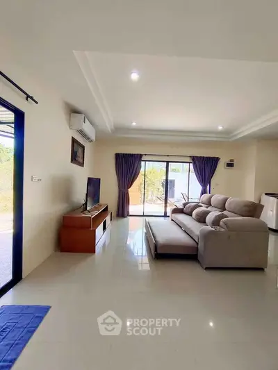 Spacious living room with modern sofa and large windows offering natural light.