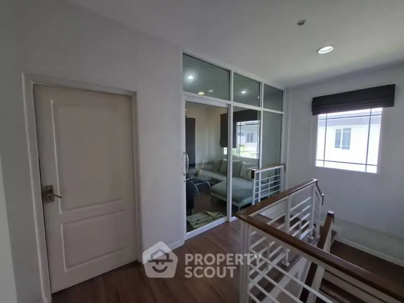 Modern interior with glass partition and wooden flooring in a bright hallway