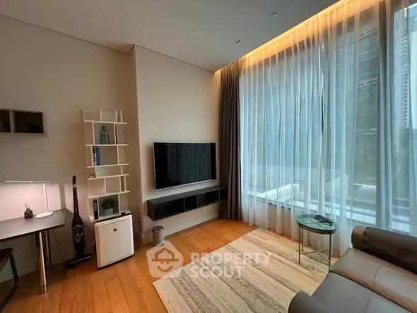 Modern living room with large window, sleek furniture, and wooden flooring in a high-rise apartment.