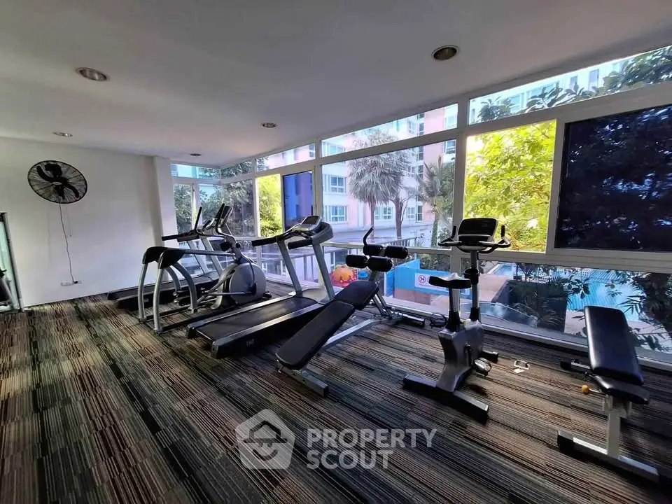 Modern gym with large windows and fitness equipment in a residential building.