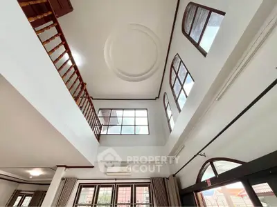 Stunning high-ceiling living room with large windows and elegant wooden accents.