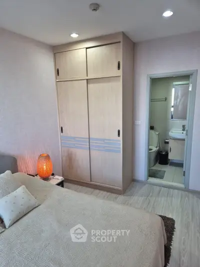 Cozy bedroom with ensuite bathroom and stylish wardrobe in modern apartment.