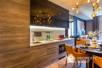 Modern kitchen with sleek cabinets and dining area featuring stylish lighting and decor.