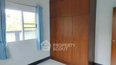 Spacious bedroom with large wooden wardrobe and natural light