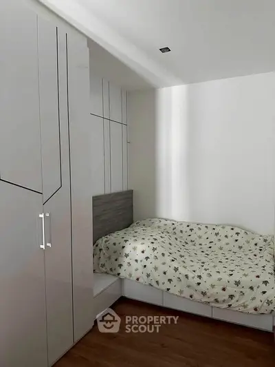 Cozy bedroom with modern wardrobe and stylish bedding in a compact space.