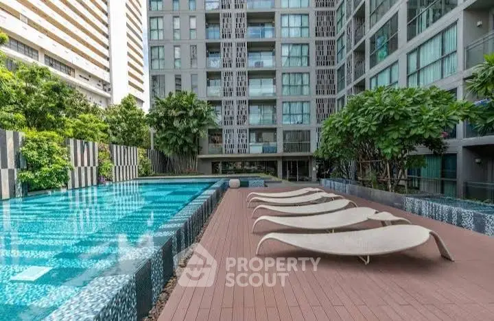 Luxurious modern apartment complex with stunning pool and sun loungers.