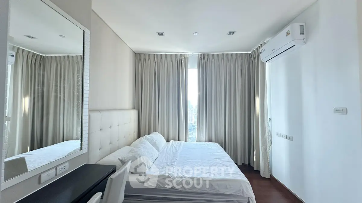 Modern bedroom with city view, featuring elegant curtains and sleek air conditioning unit.