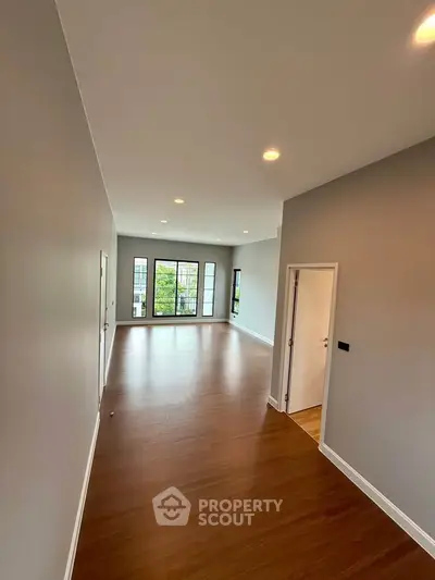 Spacious modern living room with hardwood floors and large windows offering natural light.