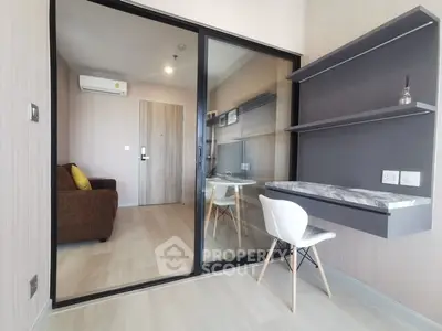Modern apartment interior with study area and glass partition, featuring sleek design and natural light.